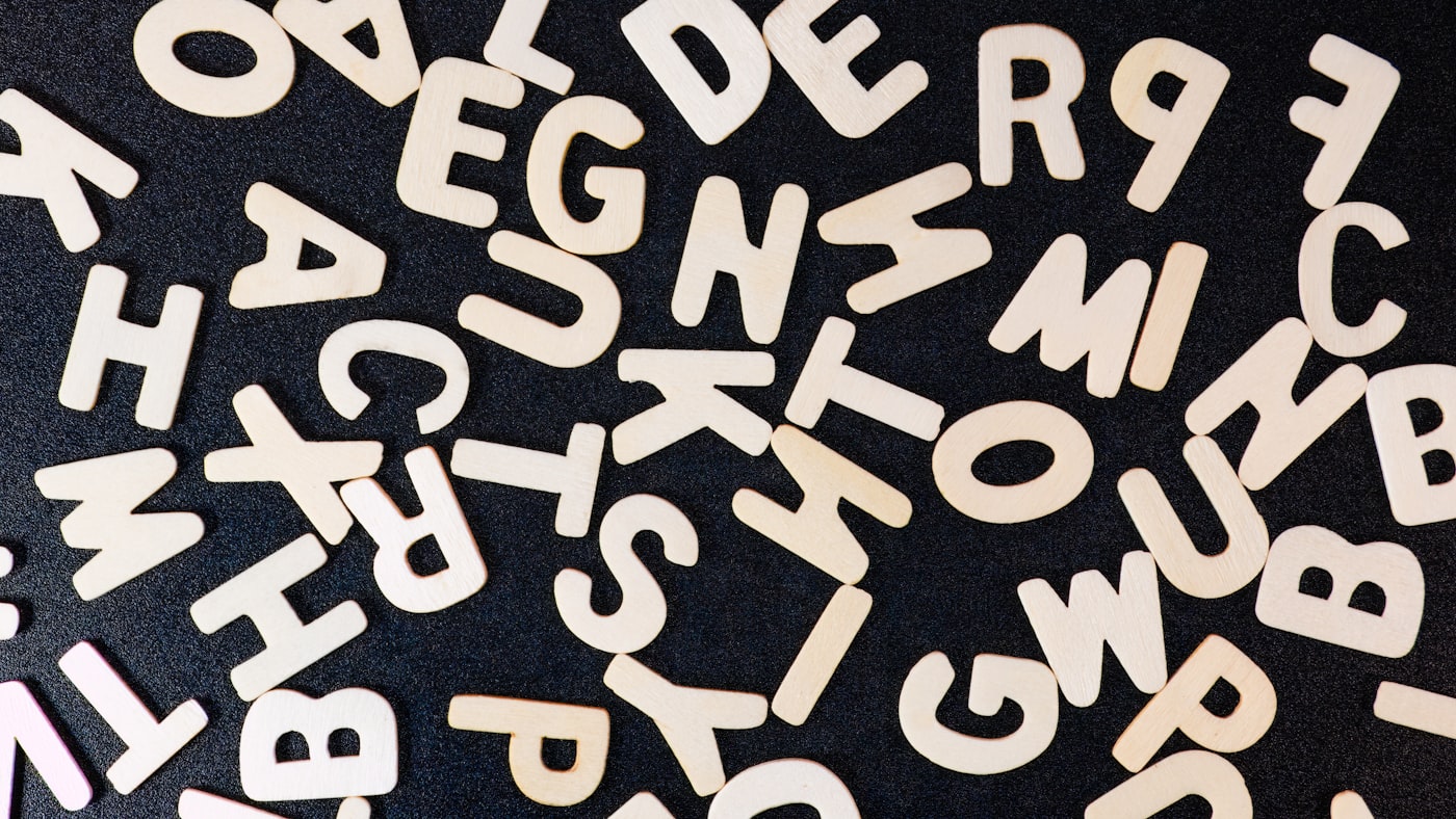 Close-up of small hands arranging wooden letters on a soft linen mat.