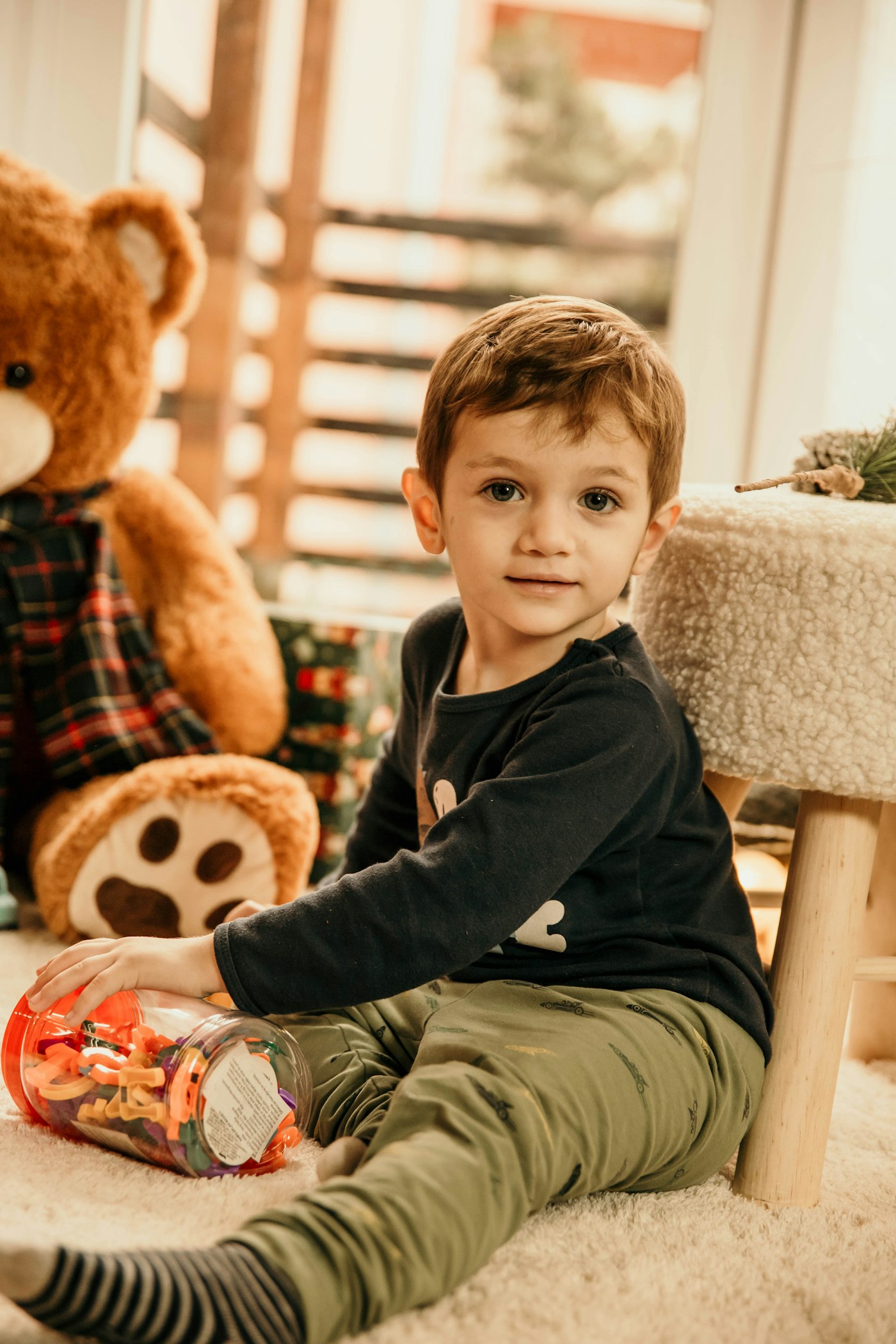 A softly lit classroom corner with wooden toys and a child gently tracing letters in a sand tray.