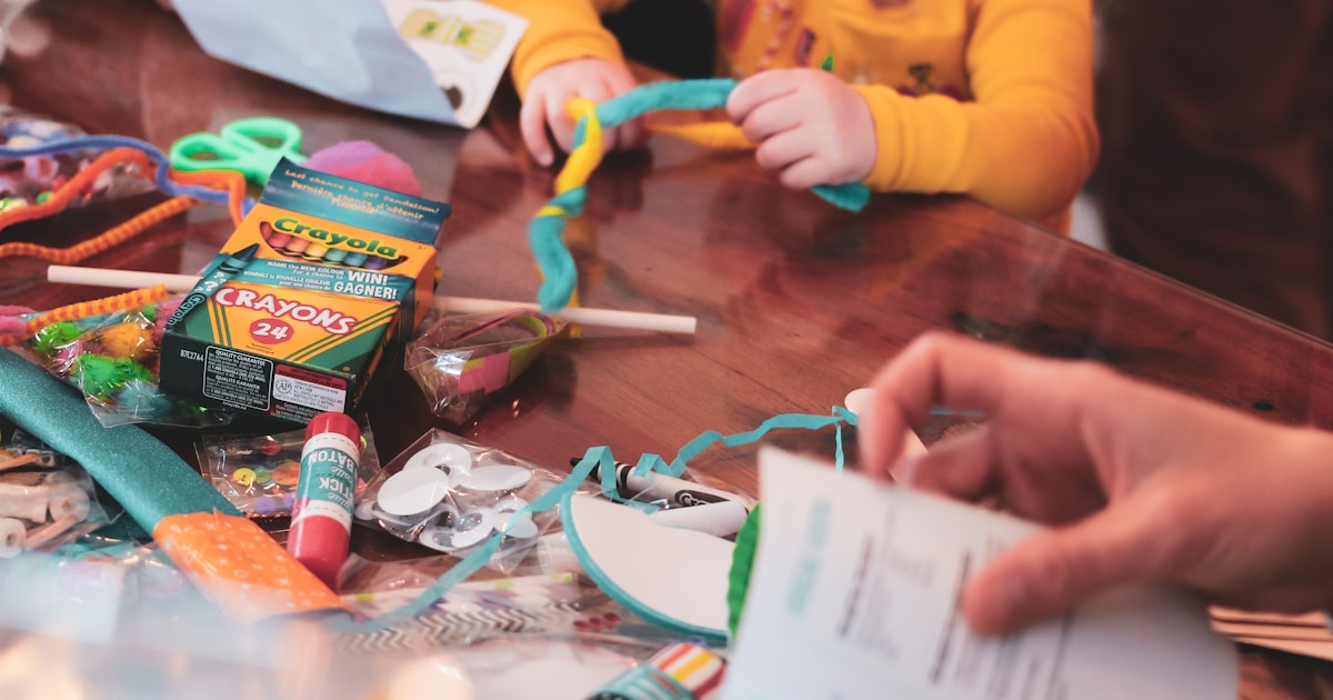 a young girl sitting at a table with lots of craft supplies