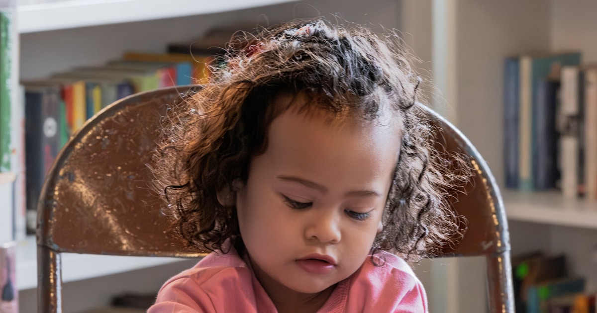 Young child focused on a book in a library.