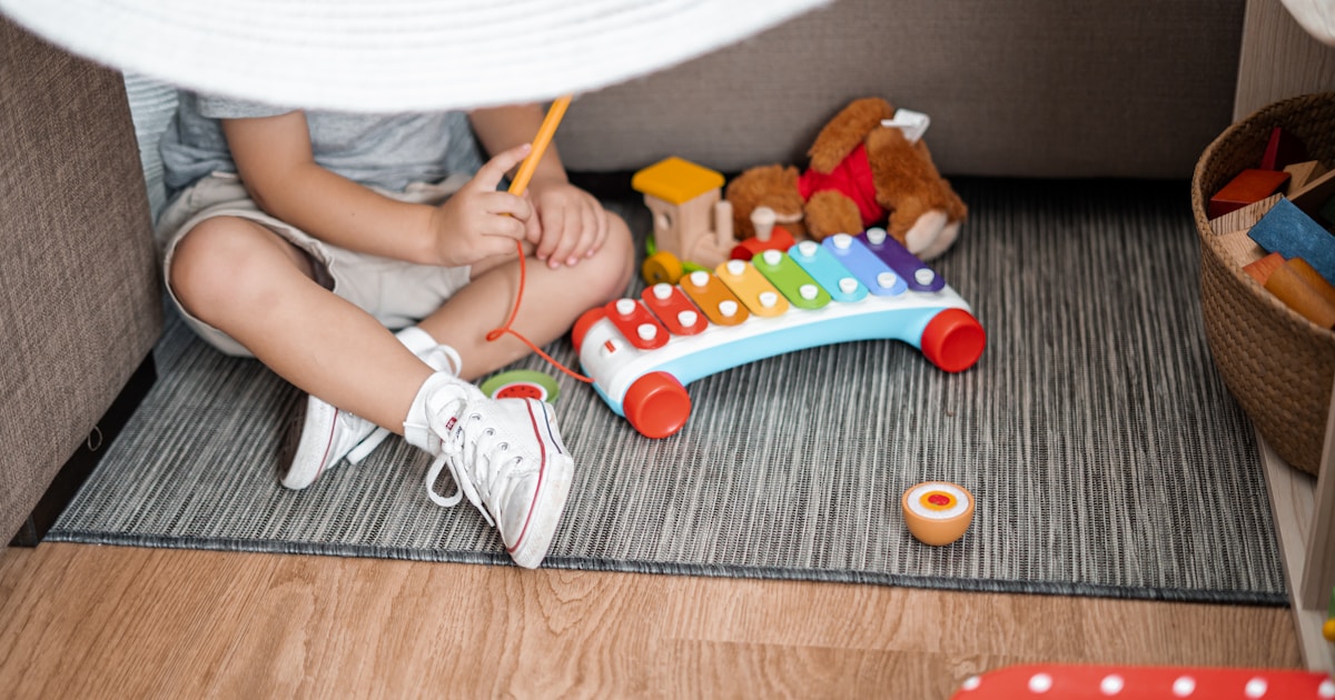 child sitting on floor and playing with xylophone toy