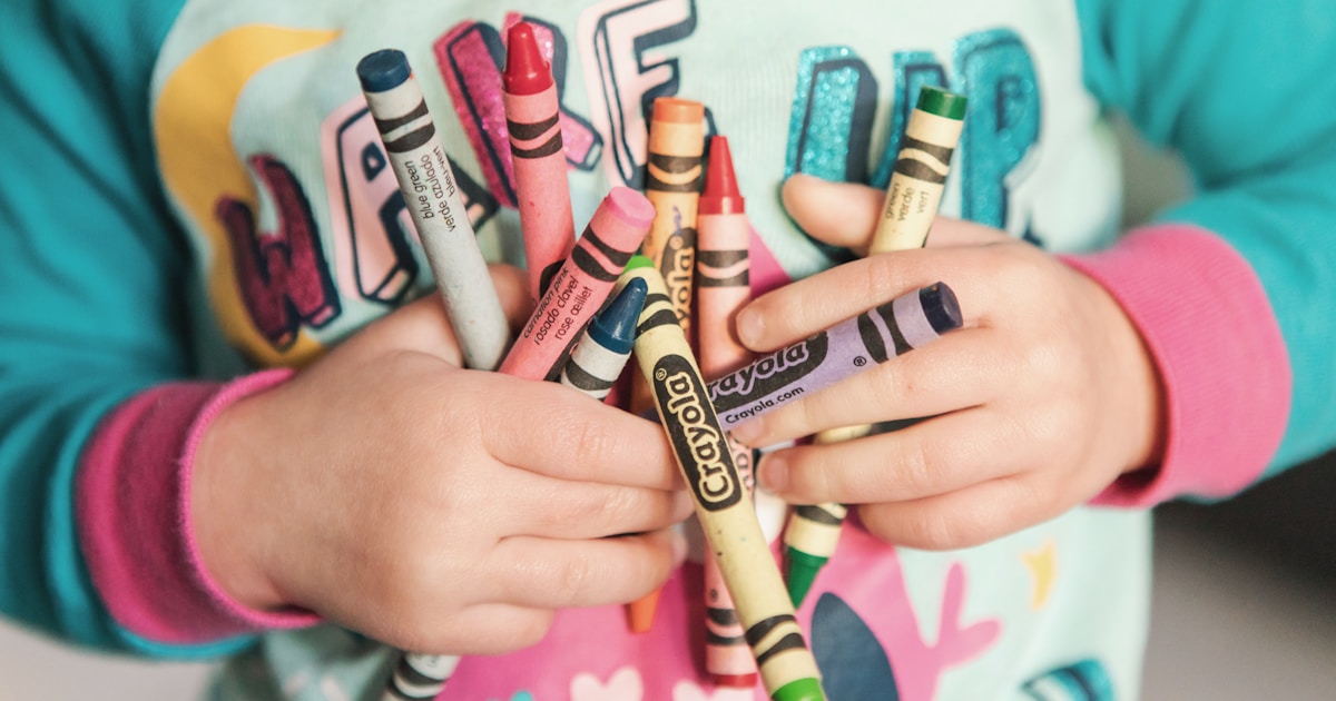 toddler holding assorted-color Crayola lot