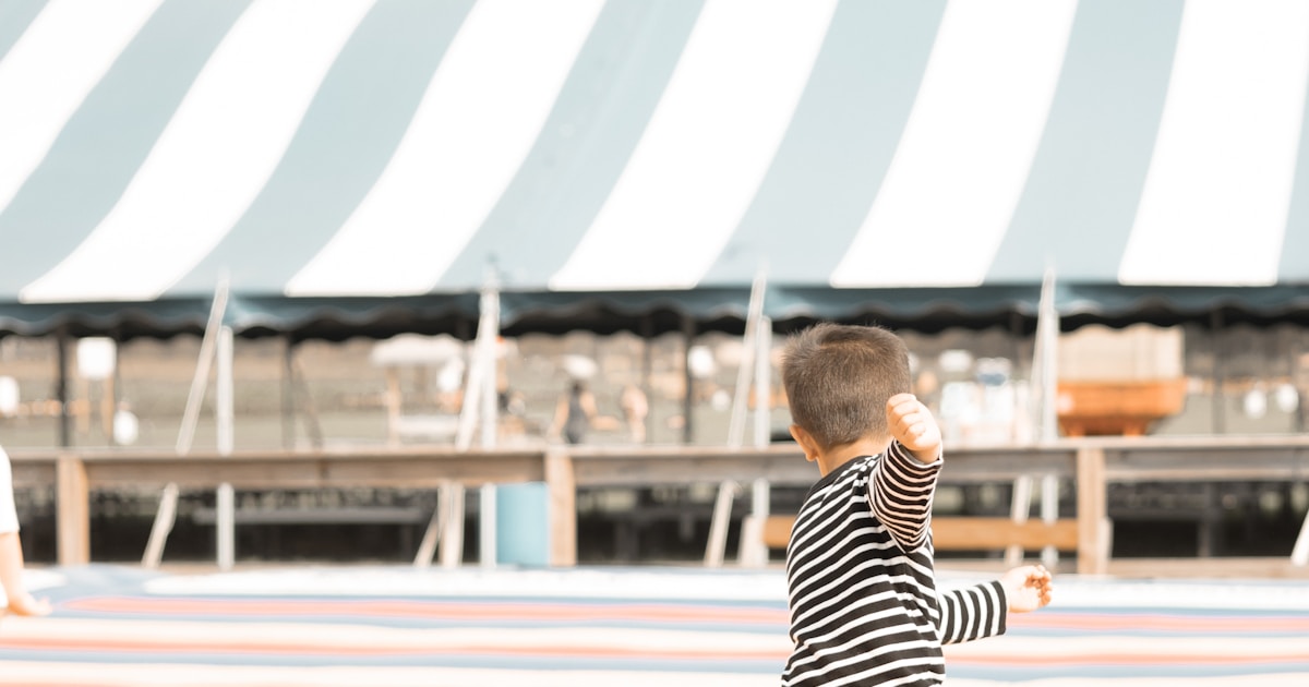 A little boy standing on top of a surfboard