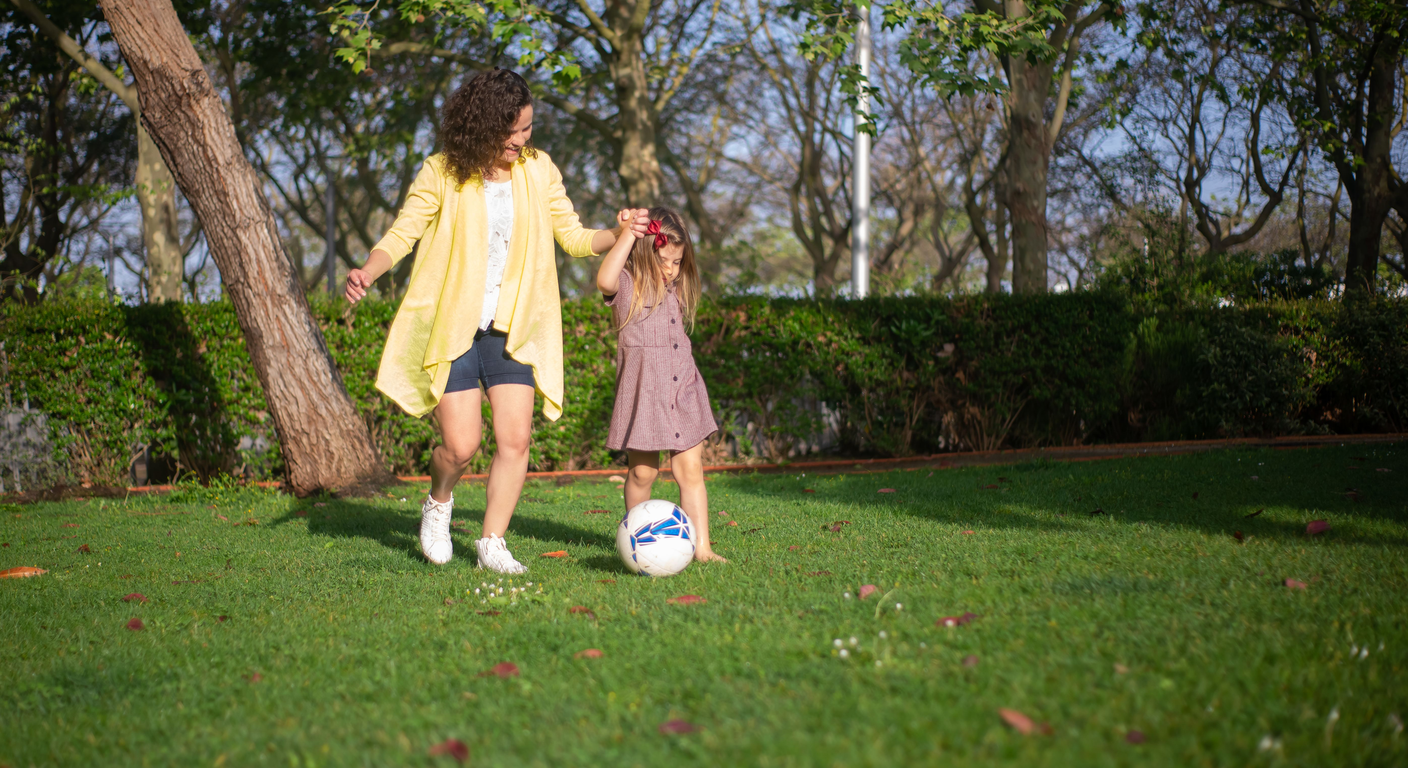 Mother and child playing outside in a park, smiling and happy.