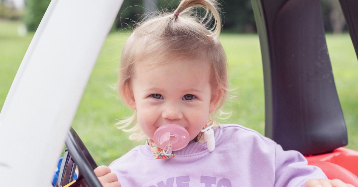 Young child with pacifier in toy car