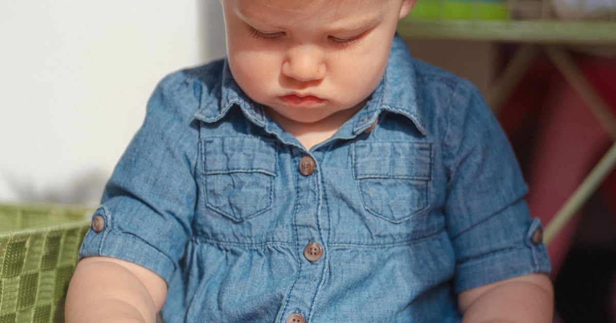 a baby sitting on the floor reading a book
