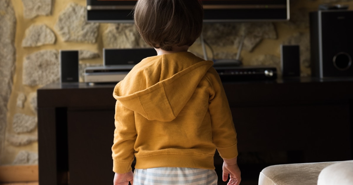 A small child standing in front of a television