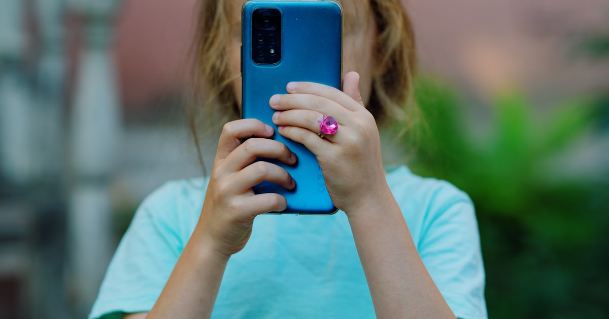 a little girl taking a picture with her cell phone
