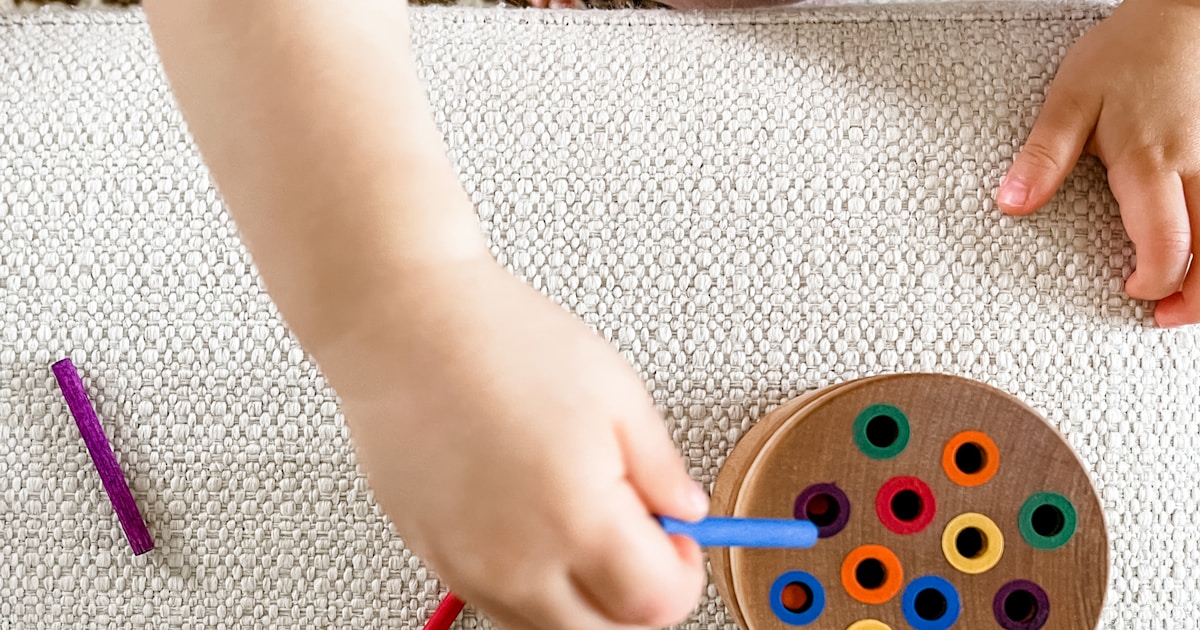 person holding blue and green round plastic toy