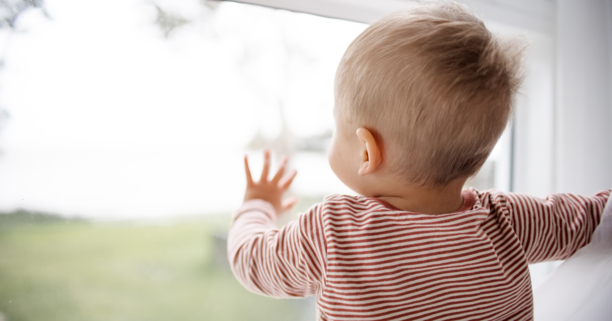 child in red and white striped shirt looking out the window