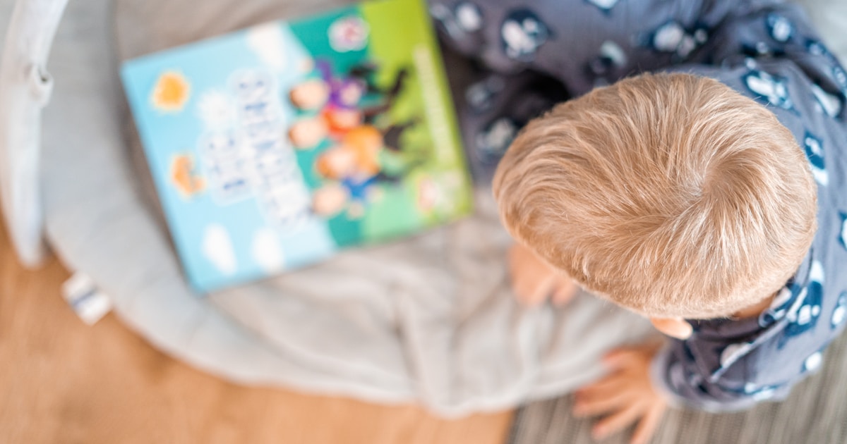 a little boy reading a book on a bed