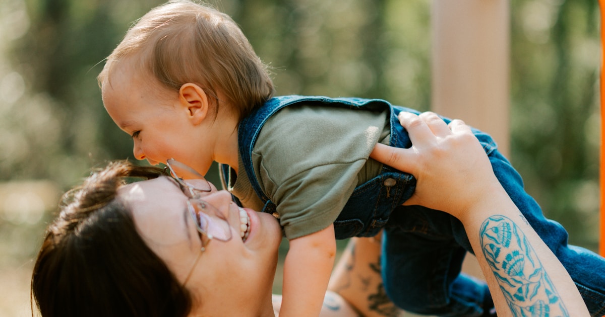 Mother holds baby up at playground
