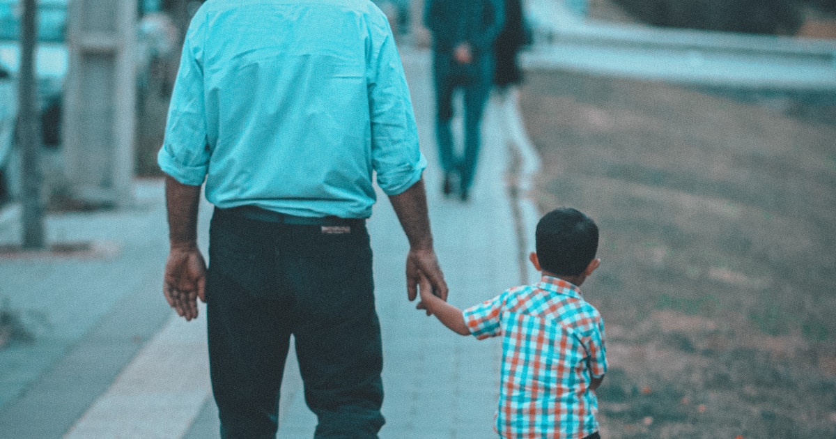 a person and a child walking on a sidewalk