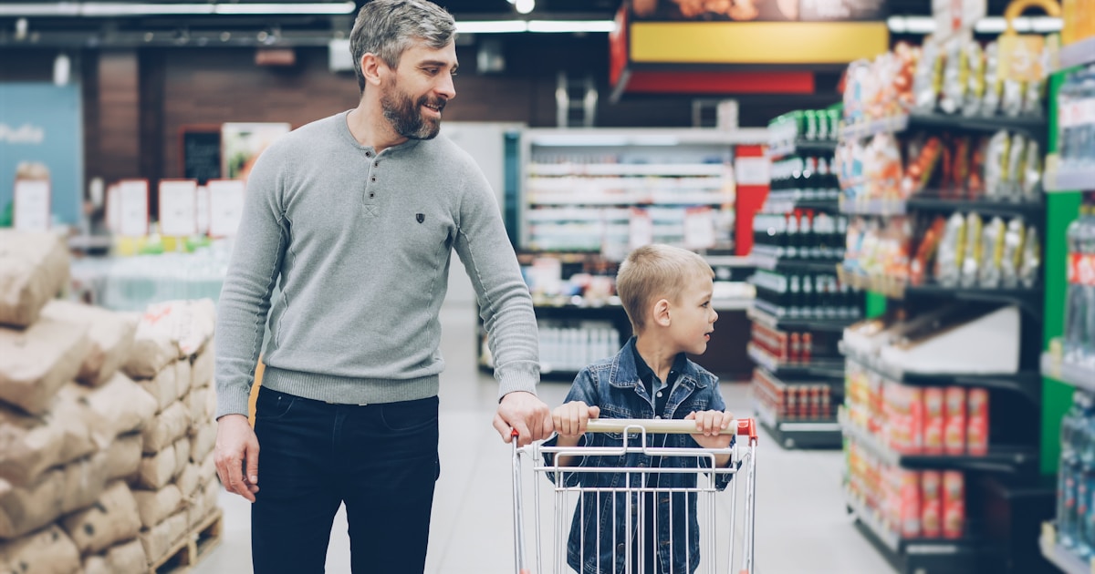 A father and son shop together in a supermarket.
